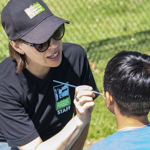 Parks and Recreation employee painting a boy's face