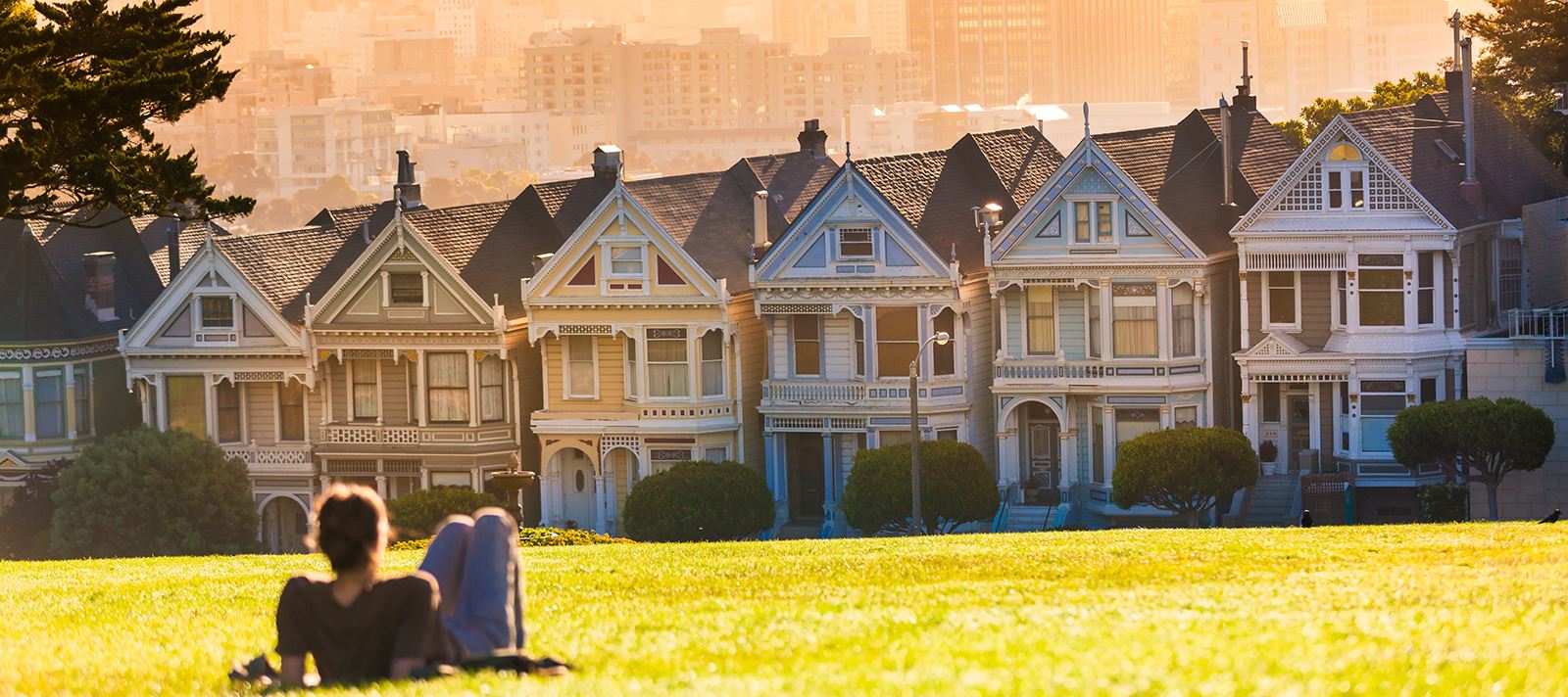 Woman sitting in the grass looking at a row of houses