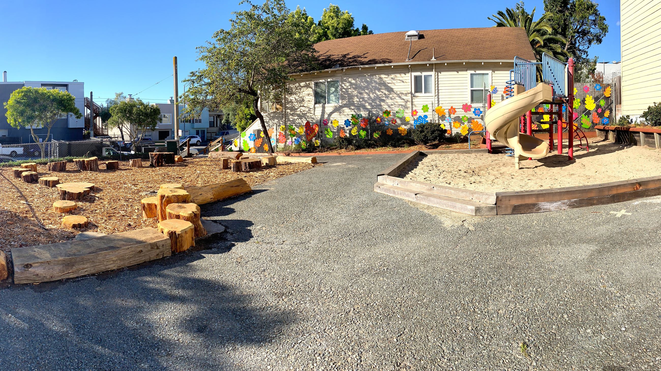 Play structure with slide and circle of logs on wood chips.