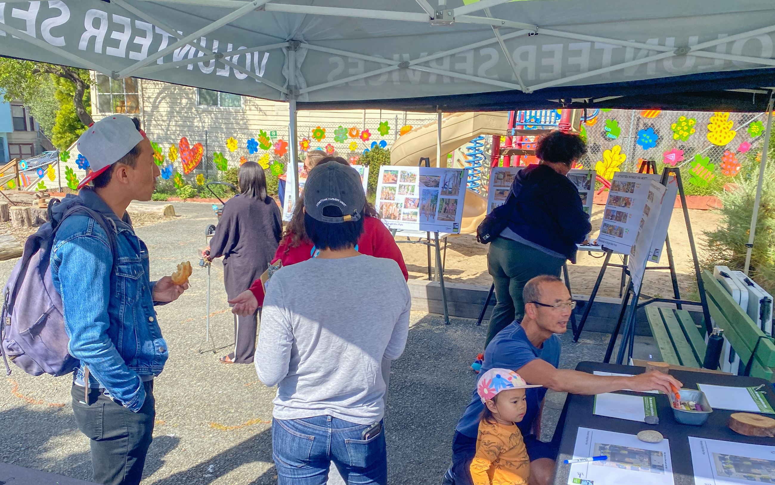 Members of the community gather under the feedback tents