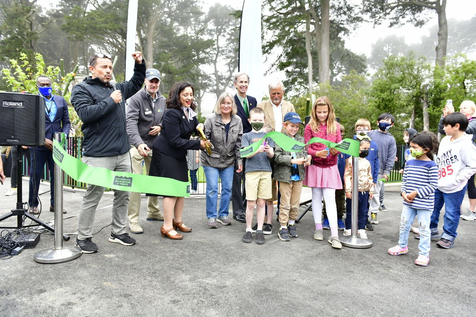 Ribbon cutting ceremony showing multiple people behind a green ribbon Ribbon cutting ceremony showing multiple people behind a green ribbon